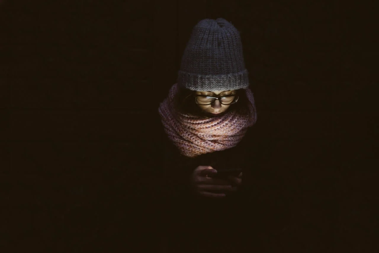A woman using phone tapping app on her mobile in the dark